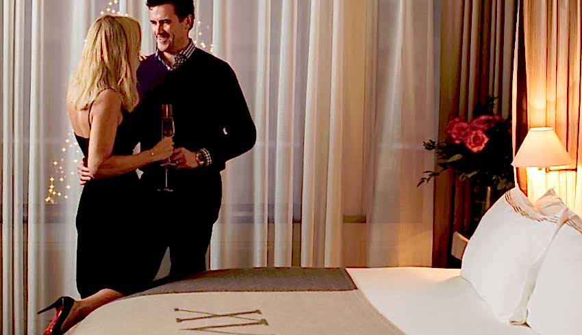 beautiful couple standing by a XV Beacon bed with roses to the side